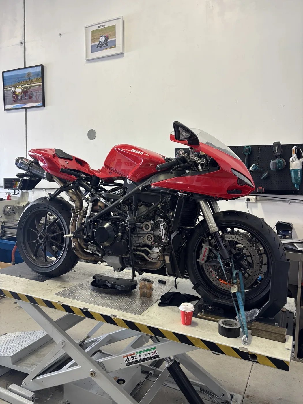 Red sport motorcycle with bodywork removed on a Motopro workshop lift